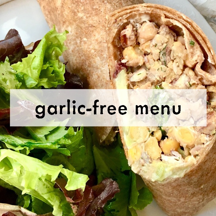 A fresh, garlic-free wrap filled with chickpeas and greens is paired with a vibrant side salad of mixed greens. A "garlic-free menu" label is overlaid.